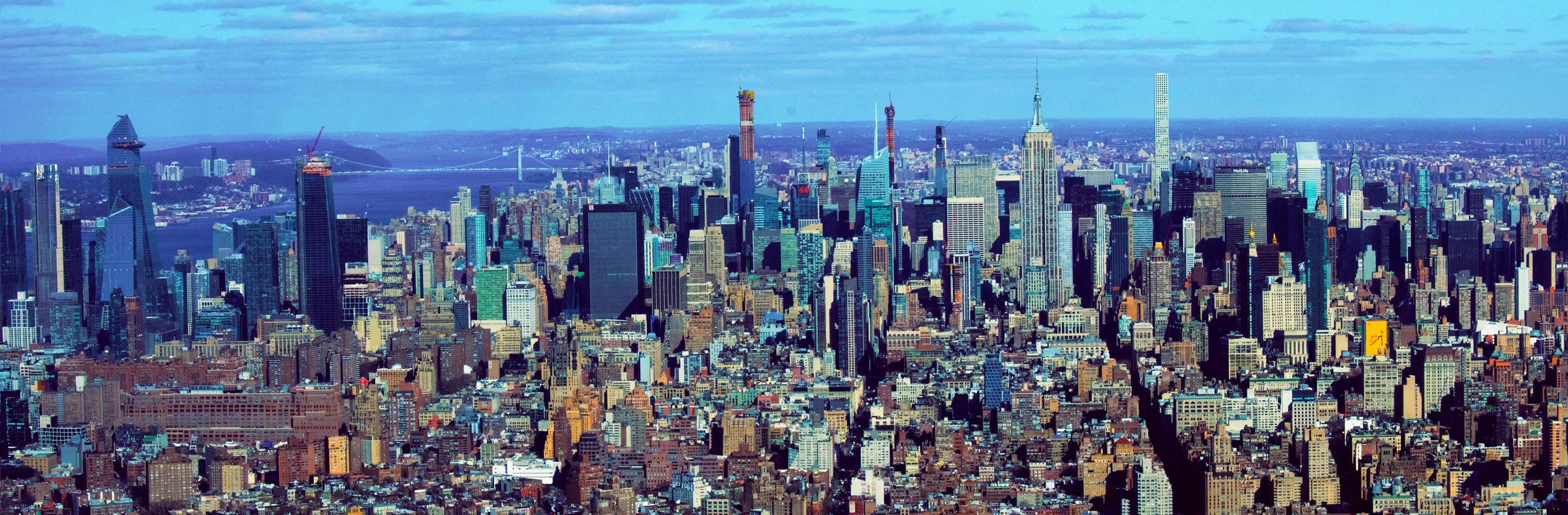 From the Deck — One World Trade Center · New York. Shot from the observation deck of One World Trade Center — the new tower, the deck, not the old skyline. Midtown in one pull: the Empire State, the rivers, the far bridges, every rooftop the light could reach. This is the tapestry. Kept at the original resolution. The largest frame in the house because it earned it.