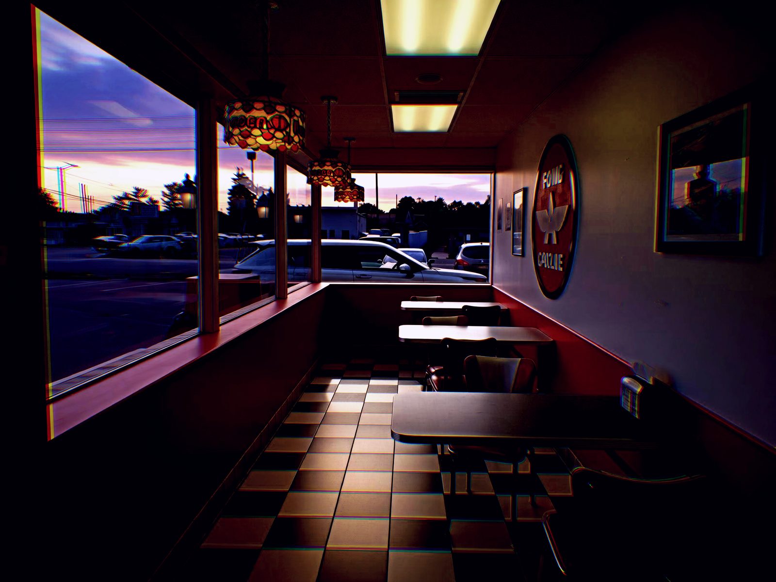 Last Sitting — Lancaster County. A diner booth row at sunset. Stained-glass lamps, checkerboard floor, nobody in the seats. The parking lot is doing the lighting.