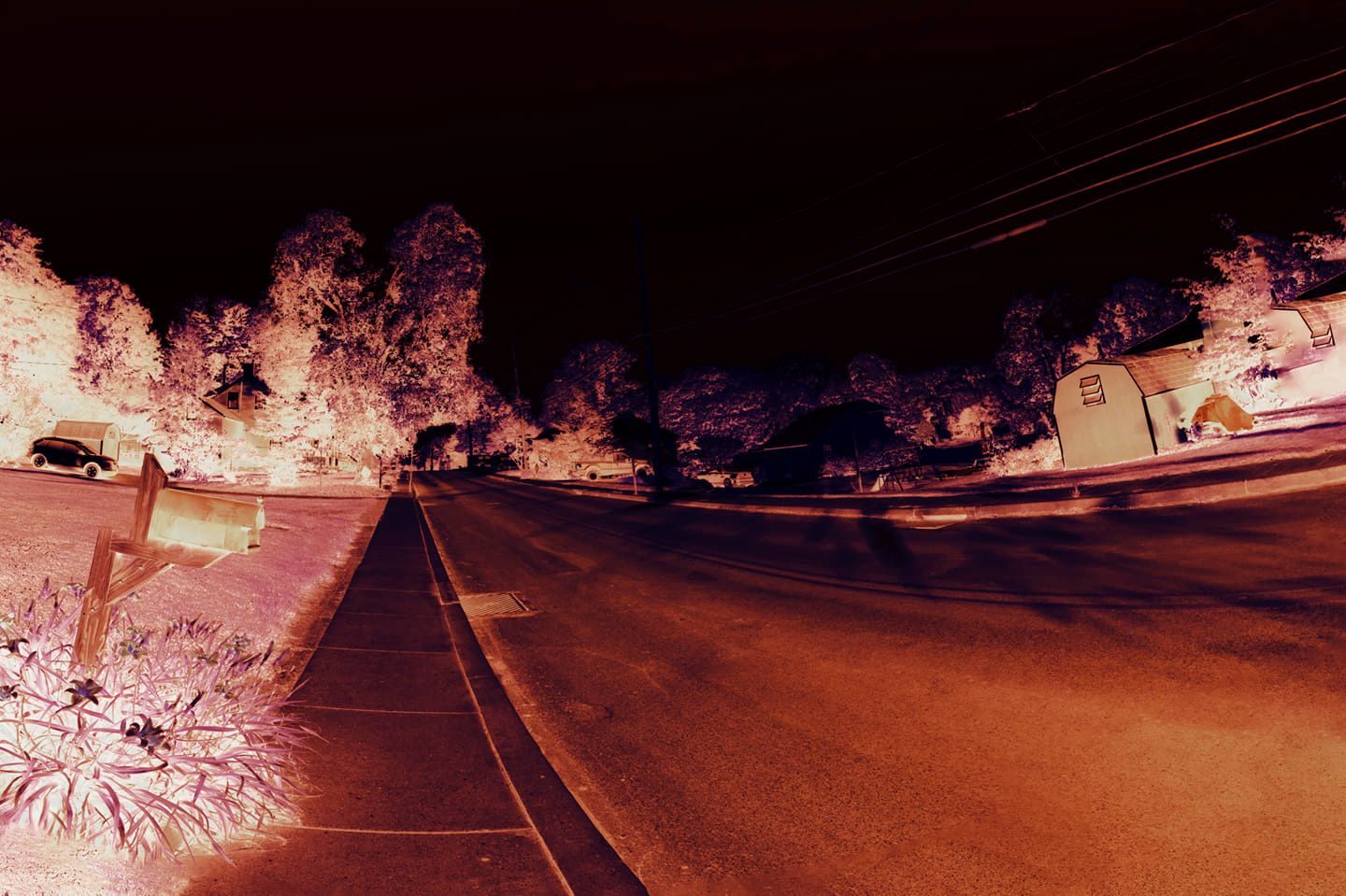 Night on the Corner — Lancaster County. Infrared night on a suburban corner. Mailbox, grass, a barn-shaped garage. The trees went white. The asphalt stayed orange.