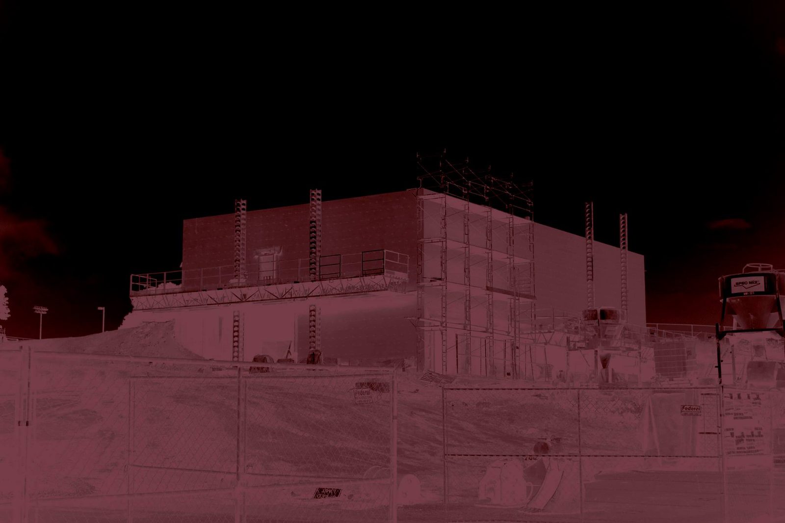 Raised — Lancaster County. A building going up behind a fence. Red grade, night. Construction as a still life.