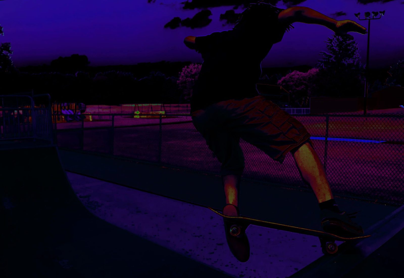 The Gap — Lancaster County. A skateboarder in the air over a ramp, dusk going purple. Motion held. The fence and the field stay put.