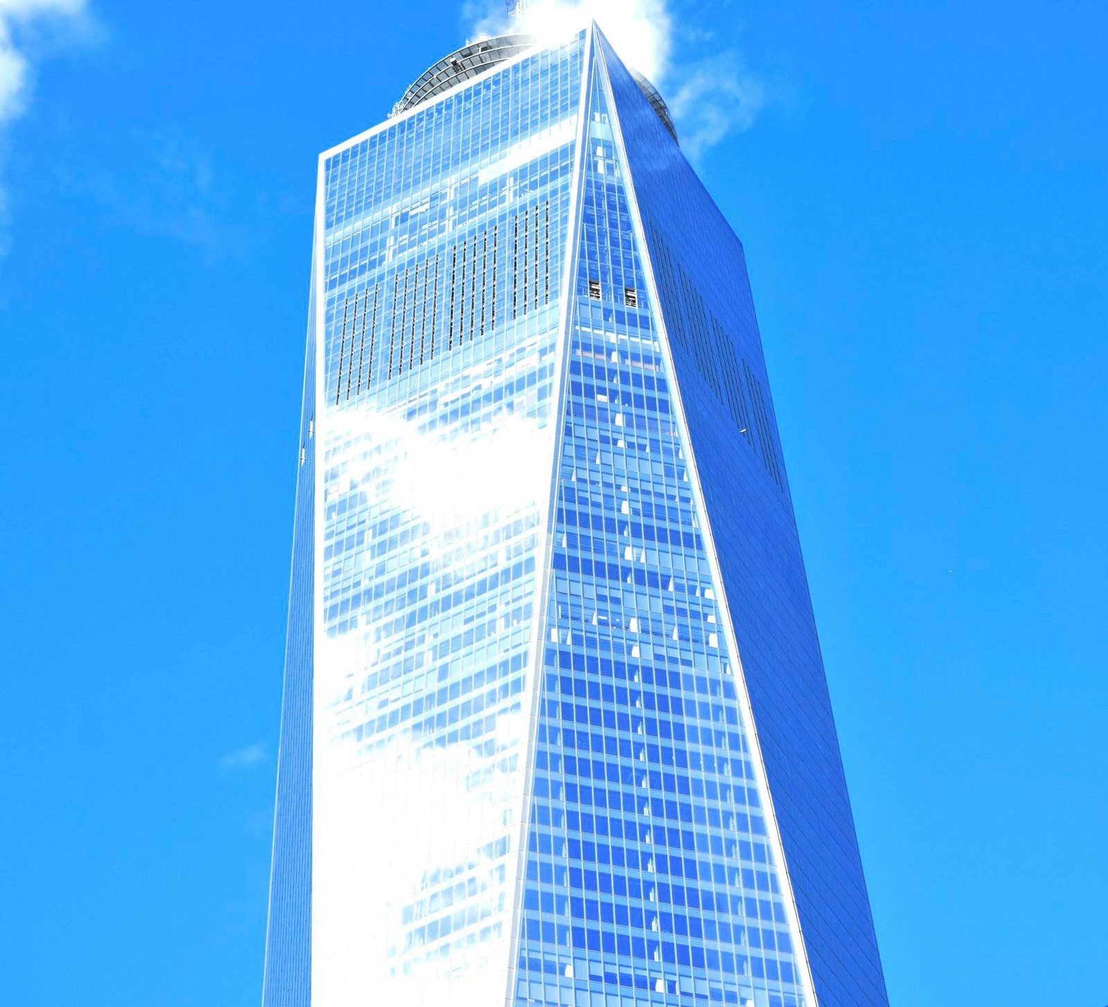 The Spire — New York. One World Trade against a hard blue. Not the county. The camera still went, and the glass still threw the sun.