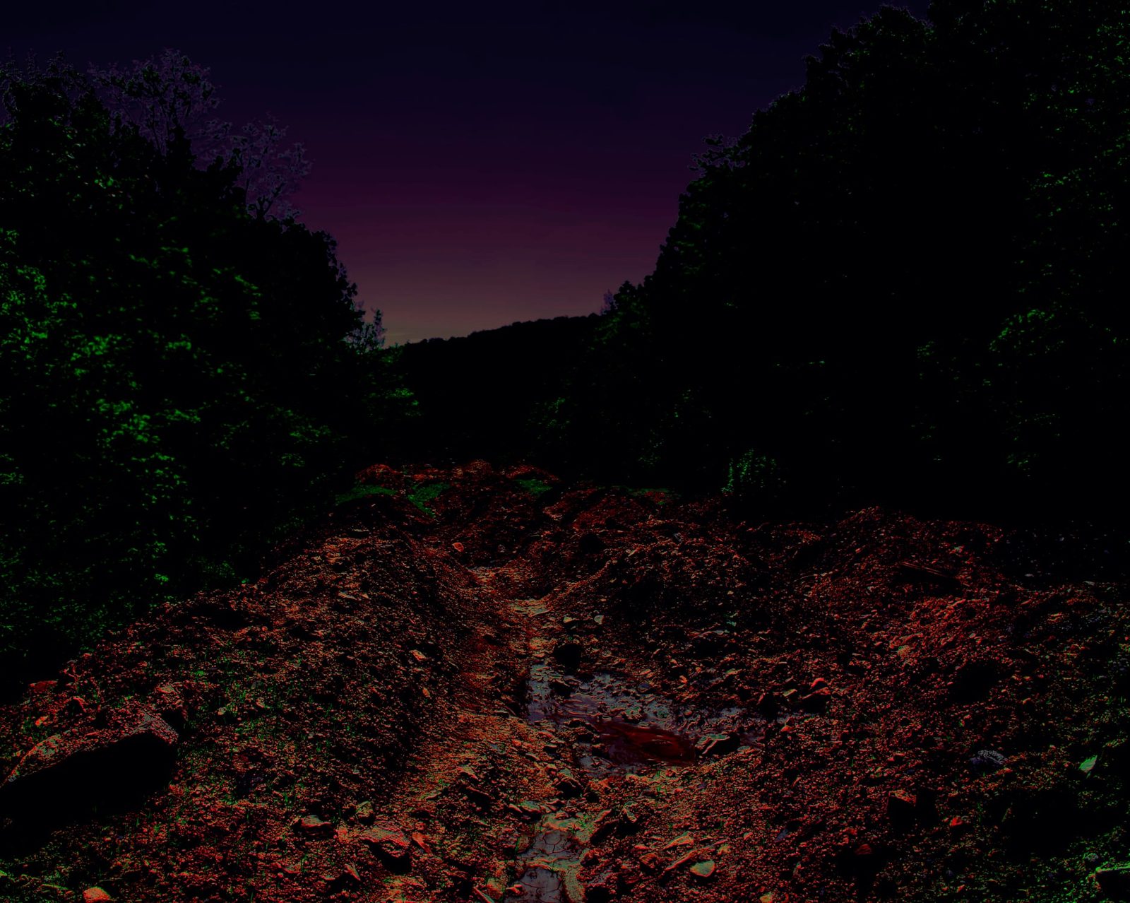 Unpaved — Lancaster County. Dirt, puddles, a last strip of dusk. Not a highway. The kind of road that still remembers farm traffic.
